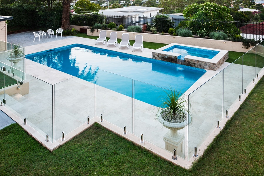 Modern Swimming Pool Covered With Glass Panels Beside A Lawn Modern swimming pool covered with glass panels beside a green lawn garden including trees and chairs